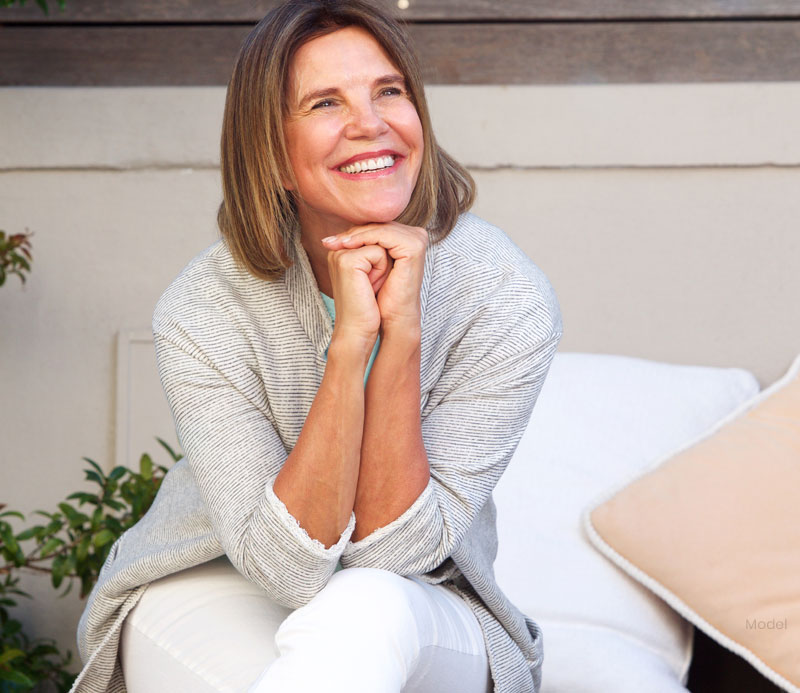 Older woman happily resting her elbows on her lap