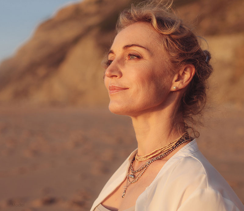 Profile headshot of a woman on a beach at sunset